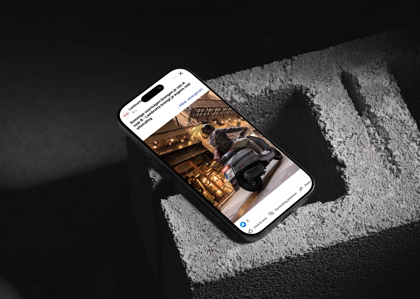 Smartphone met afbeelding van persoon op motorfiets liggend op ruwe betonnen ondergrond binnen met sfeerverlichting